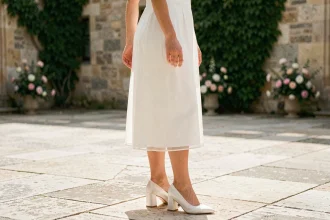 Femme en robe de mariée blanche portant des chaussures de mariage blanches à talon bloc bas sur un parvis en pierre d'un château français